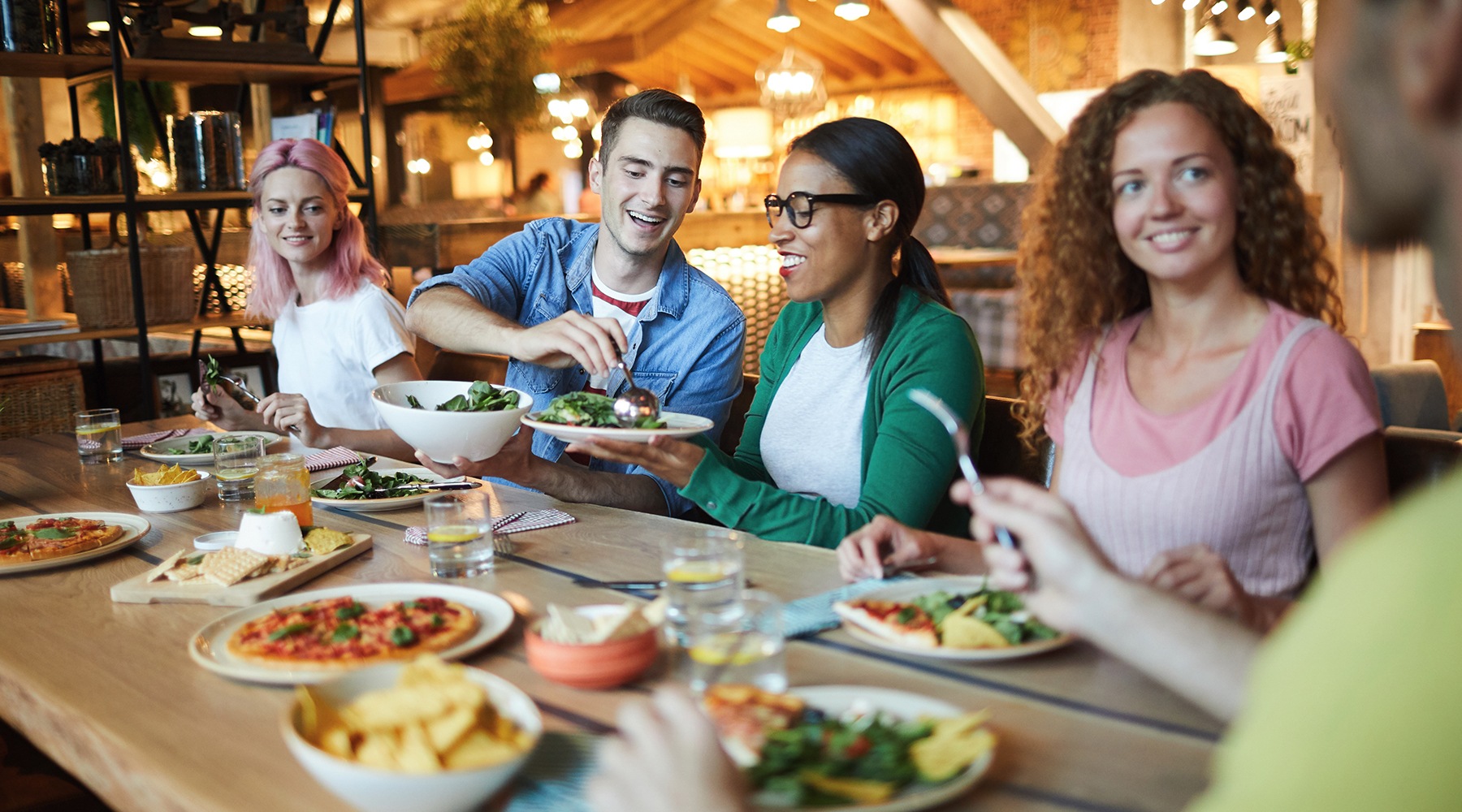 friends eating together at a large table in a restaurant friends eating together at a large table in a restaurant