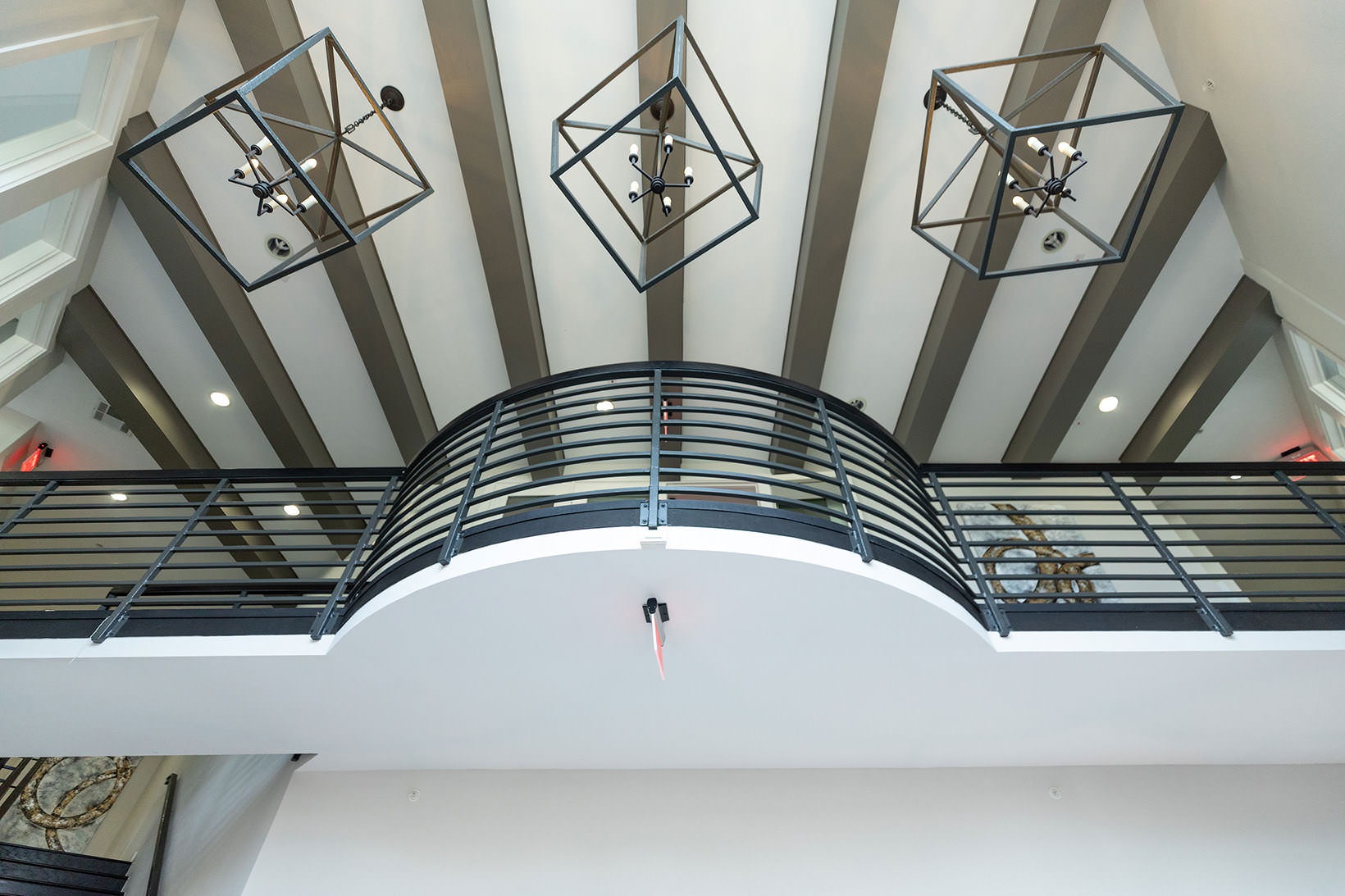 Lobby view of second floor balcony and stylized lighting in lobby